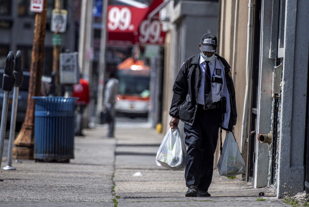 A Man Wearing A Security Guard Uniform and a Mask Walks in Hempstead, New York Carrying Groceries