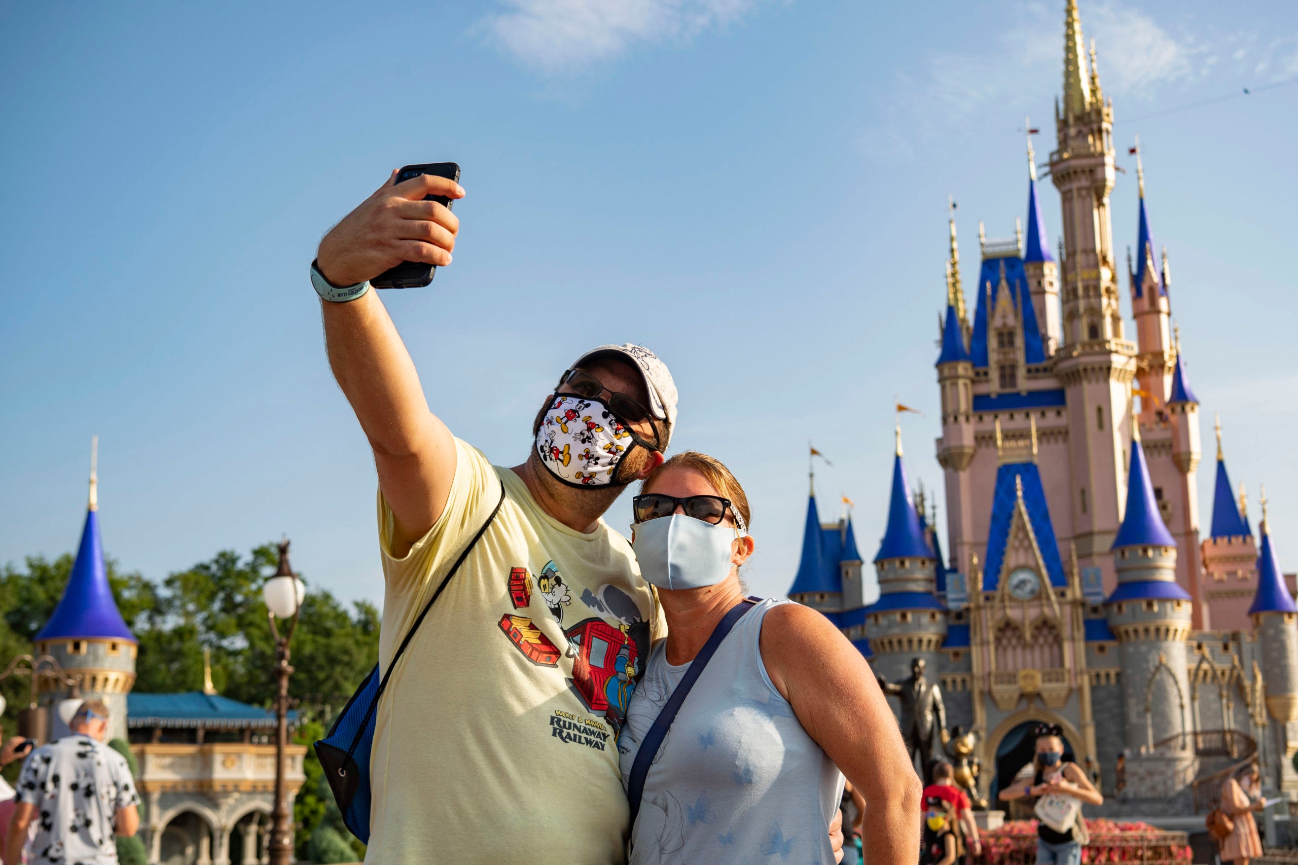 In this handout photo provided by Walt Disney World Resort, guests stop to take a selfie at Magic Kingdom Park at Walt Disney World Resort on July 11, 2020 in Lake Buena Vista, Florida. July 11, 2020 is the first day of the phased reopening. (Photo by Matt Stroshane/Walt Disney World Resort via Getty Images)