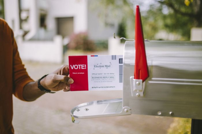 Man putting voting ballot to mailbox.