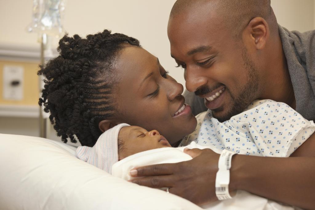 Black couple in hospital looking at newborn baby