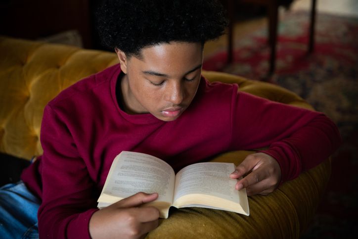 Young boy reading a book at home