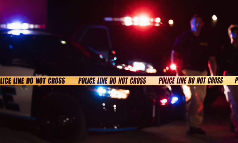 Two police officers behind crime scene tape