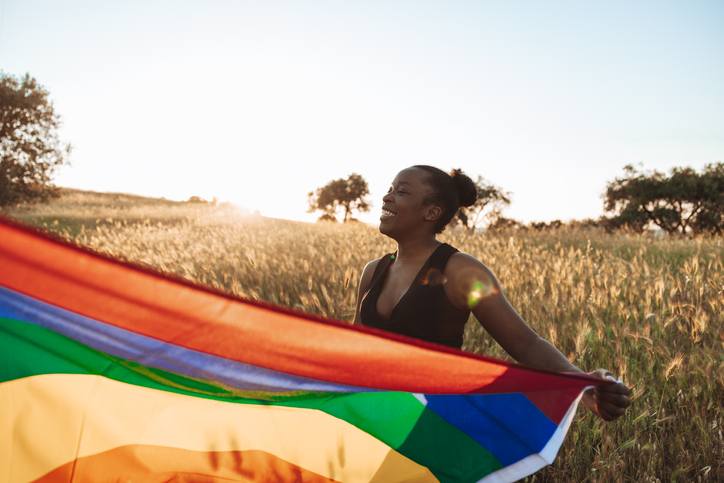 LGBTQ+ pride, woman holding a rainbow flag