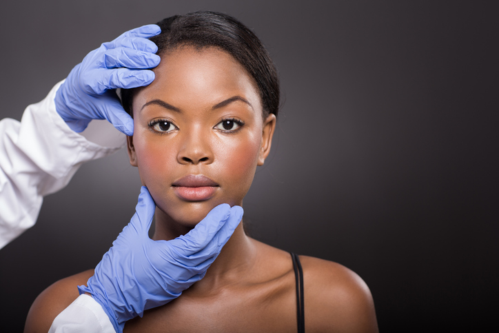 dermatologist checking african woman face skin