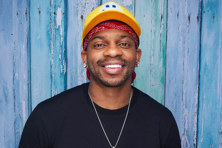 Jimmie Allen in yellow baseball cap and black tee