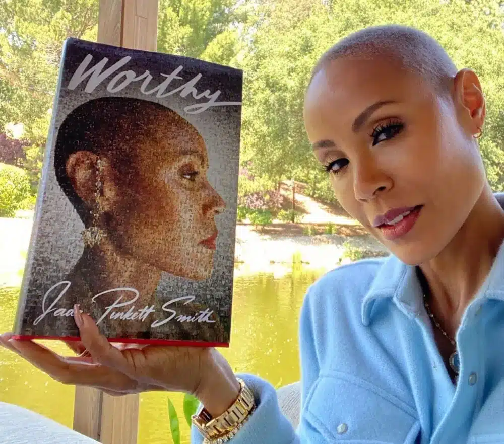 Jada Pinkett Smith holds up a copy of her book, 