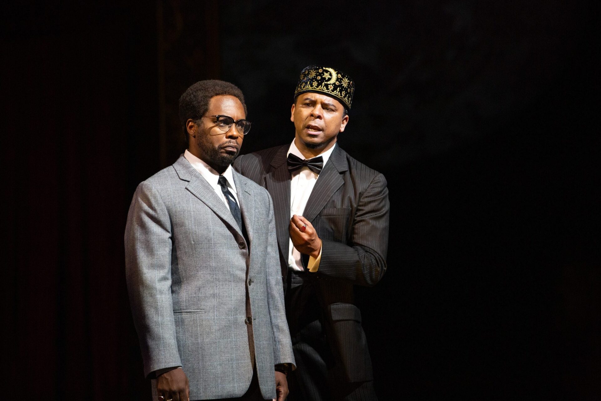 <strong>Reimagining Malcolm X Through Opera</strong>” width=”400″ height=”266″ />Scenes from X: The Life and Times of Malcolm X </p>
<p>The director’s understanding of Afrofuturism is simple: it is imagining the Black body in the future.”Fully functional and in control of its own story,” he says.</p>
<p>“I think that even the idea of imagining yourself out of slavery could be Afrofuturistic. As Black people, we had to imagine ourselves in a better place. Especially in this country. When [Martin Luther King Jr.] King would say, ‘I’ve been to the mountaintop.’ That to me is Afrofuturistic,” explains the director. </p>
<p>O’Hara transports the audience to both the past (journeying through Malcolm’s life) and the future throughout the entire opera. What is equally striking is that in X: The Life and Times of Malcolm X, the Met stage runneth over with Black performers.</p>
<p>Baritone Will Liverman sings the role of Malcolm X. Soprano Leah Hawkins sings as both X’s mother, Louise, and Betty Shabazz. Tenor Victor Ryan Robertson is Elijah Muhammad. Mezzo-soprano Raehann Bryce-Davis sings as Malcolm’s sister Ella. Bass-baritone Michael Sumuel is Malcolm’s brother, Reginald. The cast is joined by a chorus of regal futuristic beings (who O’Hara refers to as the AF24), as well as dancers who animate the production. The director says that the dancers are the “conscious of the story,” and for those who are not opera aficionados, they move the opera along, adding to its vibrancy. This is no traditional opera—music is jazzy at times; characters wear zoot suits and conk wigs, while singing phrases like, “shoot your shot.” For one who is a novice to the artform, you will feel satiated. </p>
<p>While X: The Life and Times of Malcolm X is a tremendous cultural moment, it also comes with an emotional cost to the cast and crew who relive X’s murder, with each curtain. </p>
<p>“Essentially, what we are doing is murdering a Black man every night and putting it on for a show. That will cost us something as people doing this every night,” says O’Hara. The director anticipates an emotional “cost” of reenacting the assassination, night after night on the Met stage. In turn, O’Hara requires the audience to experience an opera that might cause their discomfort.</p>
<p>“When you tell the truth, it is sometimes uncomfortable, and a lot of opera is about madness and murder and rape, they’re comfortable with that. But if you add race into it, people become uncomfortable.” The director explains, “Malcolm X wasn’t invested in your comfort. He was invested in the truth.”</p>
<p>O’Hara wants the audience to remember the luminary for who he was, a fearless truth teller, and what his legacy continues to be. “You can’t put Malcolm X in a box,” says the director. X was a civil rights leader: one who vociferously spoke out for Black pride and self-determination, but he was also an advocate for human rights (particularly towards the end of his life). Indeed, Malcolm X was one who believed in a liberated future. </p>
<p>“A liberated future for Black people has to be a liberated future for all people because I cannot be liberated without my sisters and brothers and my fellow comrades and all their struggles.” O’Hara continues, “Malcolm returned from Mecca as a human rights activist, and it was the first time that he had seen white people as Muslims or Asian people as Muslims. And so I think that he would have the same reaction: ‘I cannot be liberated without everyone else around me being liberated.’ And that’s what a Black liberated future looks like.” </p>
<p>‘<a href=