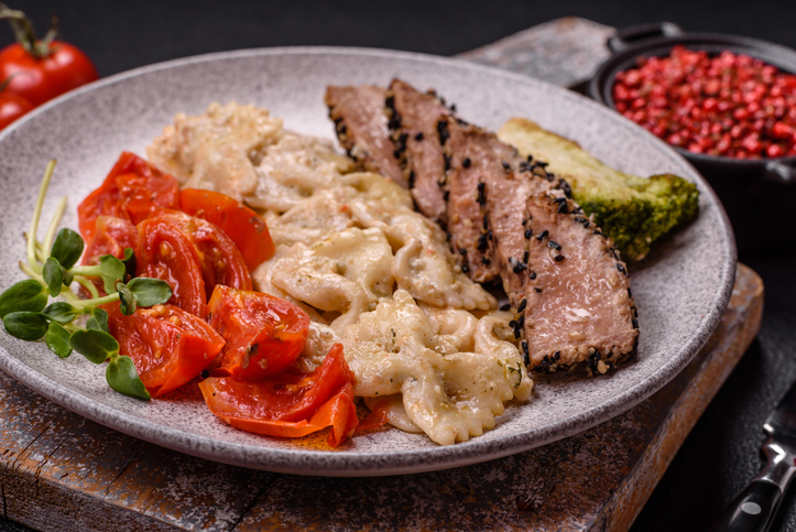 Bowl with slices of baked tuna with broccoli, tomatoes and fusili pasta