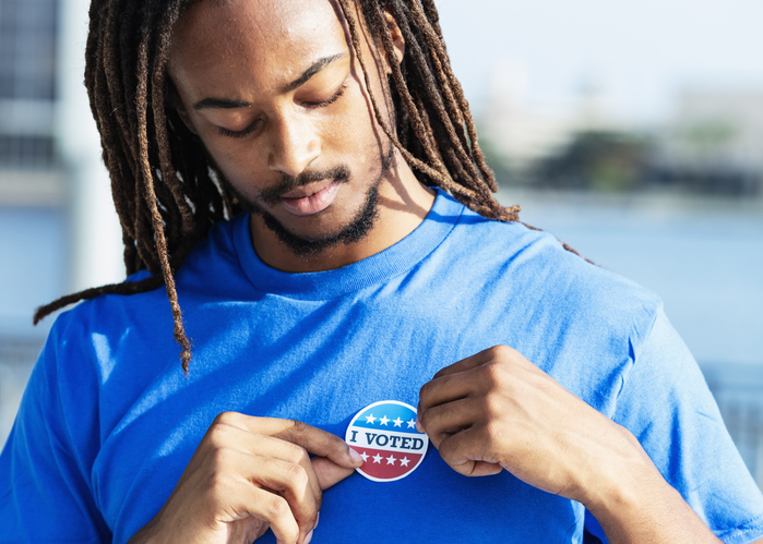 Young man putting I Voted sticker on shirt