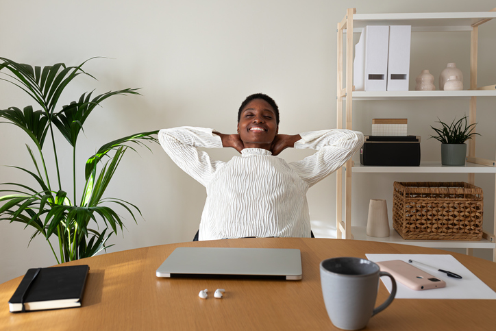 black women adhd - Young Black entrepreneur relaxing at home office with hands behind the head feeling satisfaction.