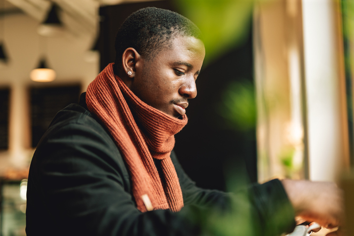 Black man is drinking coffee in cafe indoors.